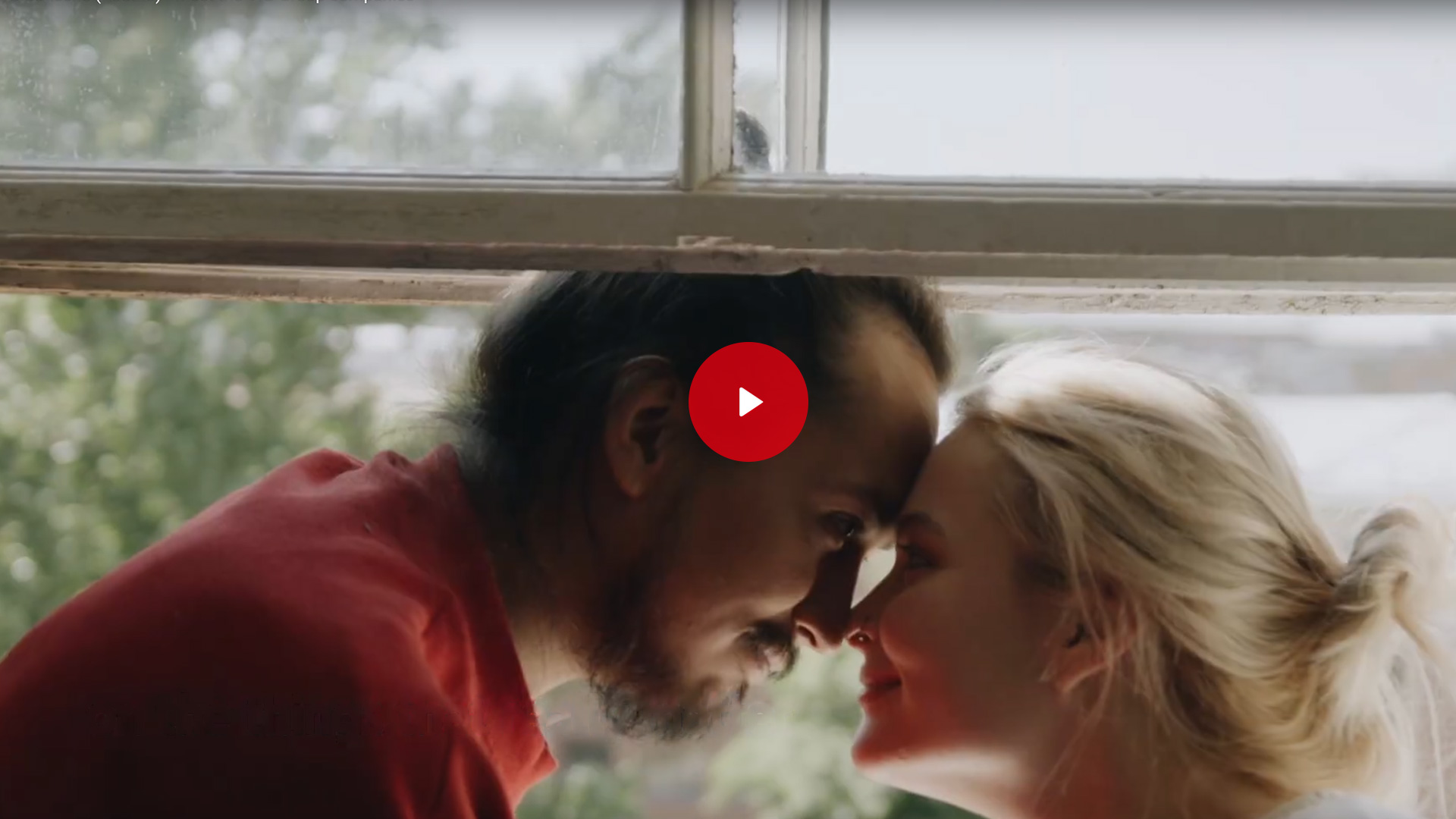 A woman and a man look at each other in love and rest their heads against each other