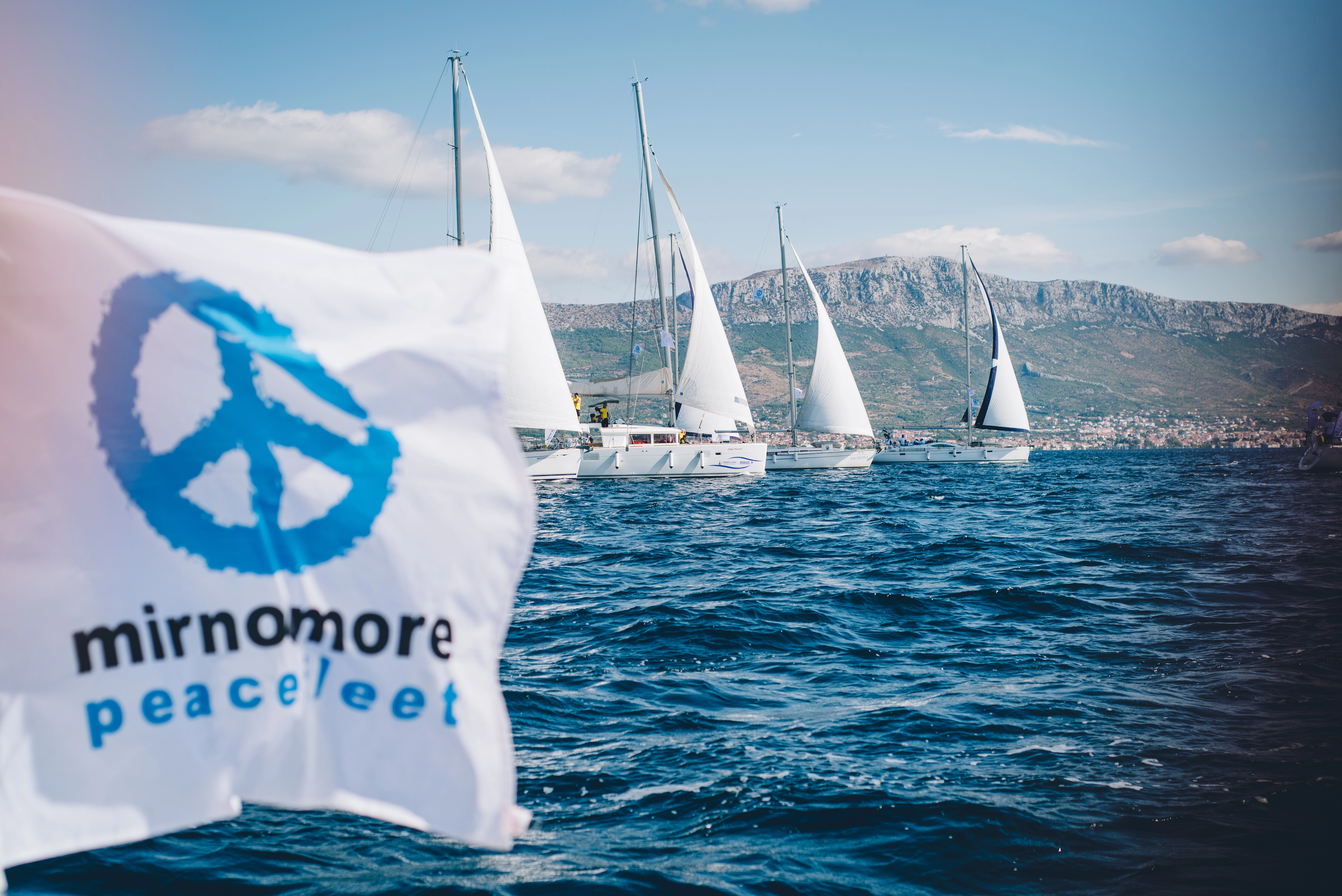 Waving flag of the peace fleet mirno more. Sailing ships in the background.