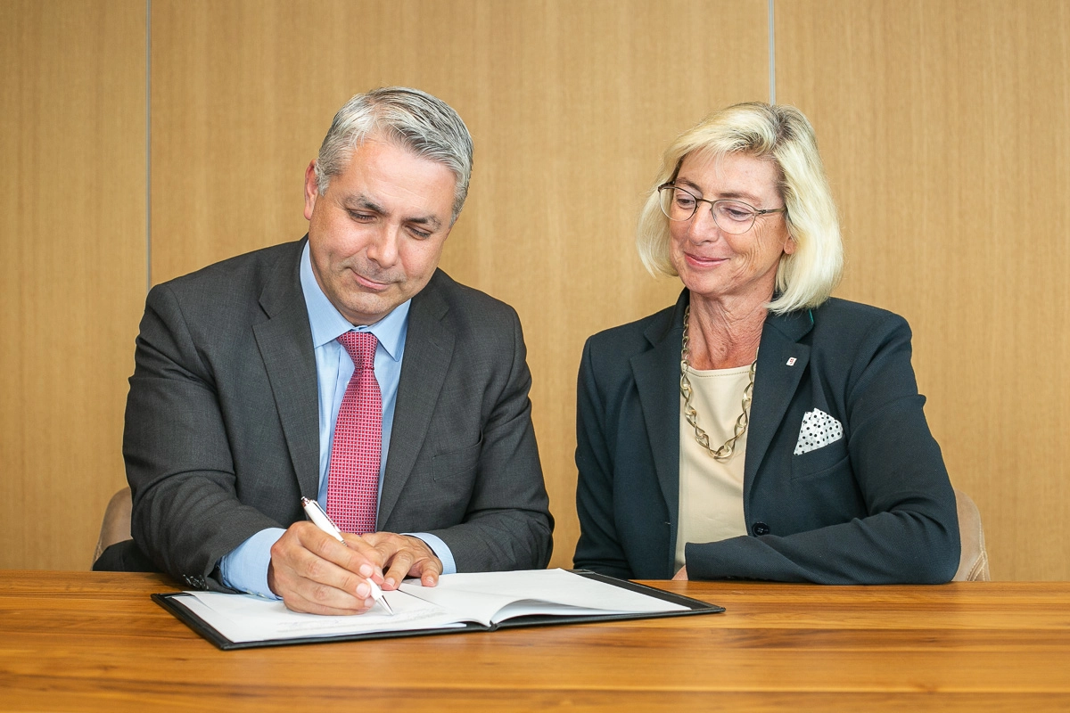 Peter Bosek (Erste Group) auf der linken Seite und Elisabeth Stadler (VIG) auf der rechten Seite unterzeichnen die Verlängerung des Kooperationsvertrages