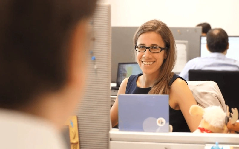 Mitarbeiterin des Actuarial Departments sitzt lächelnd an ihrem Arbeitsplatz (Video Standbild)