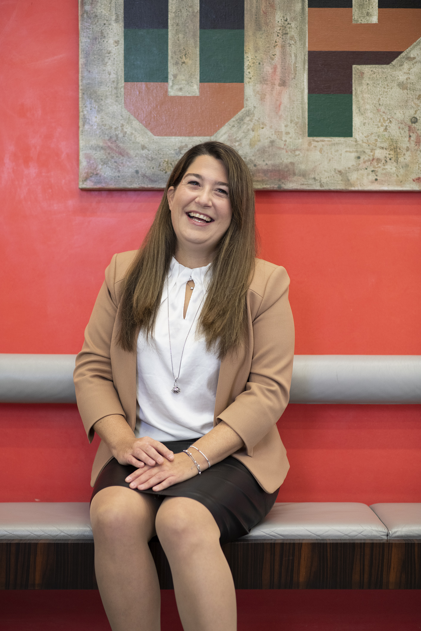 Petra, Expertin in Subsidiaries & Transaction Management sitzt auf einer Bank mit rotem Hintergrund