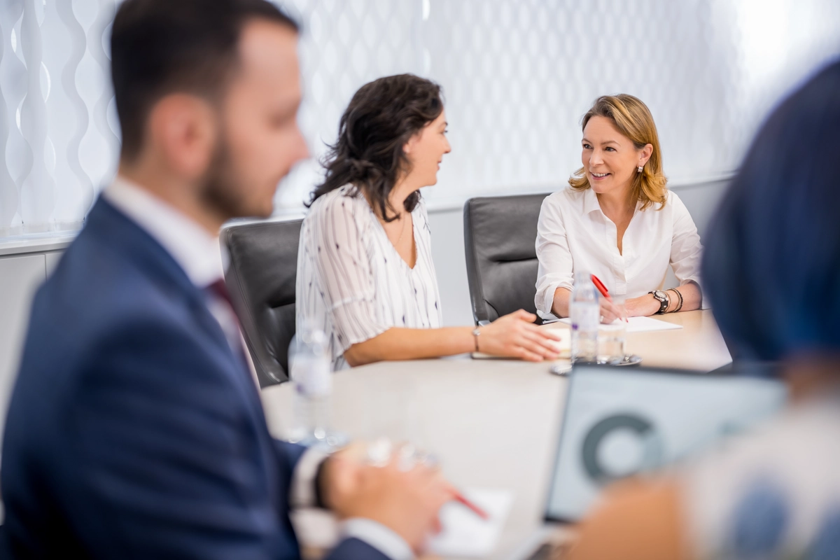 © Michael Kammeter Two women are discussing in a meeting room, one is taking notes.