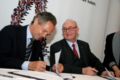 Andreas Treichl (Erste Group) on the left side and Günter Geyer (VIG) on the right side sign the contract of cooperation