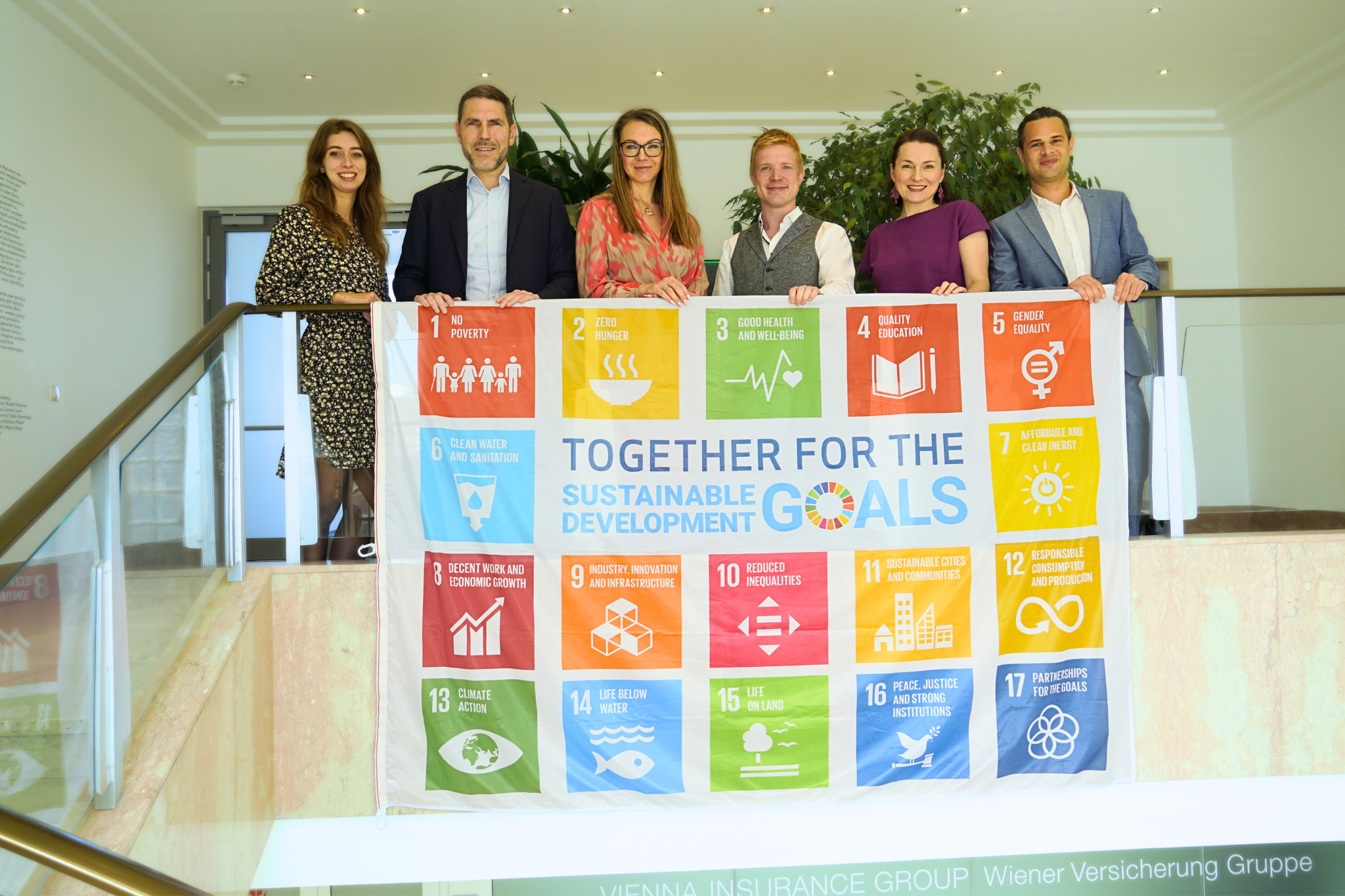 Mitarbeitende der VIG posieren anlässlich des SDG Flag Days 2024 mit eine SDG-Flagge