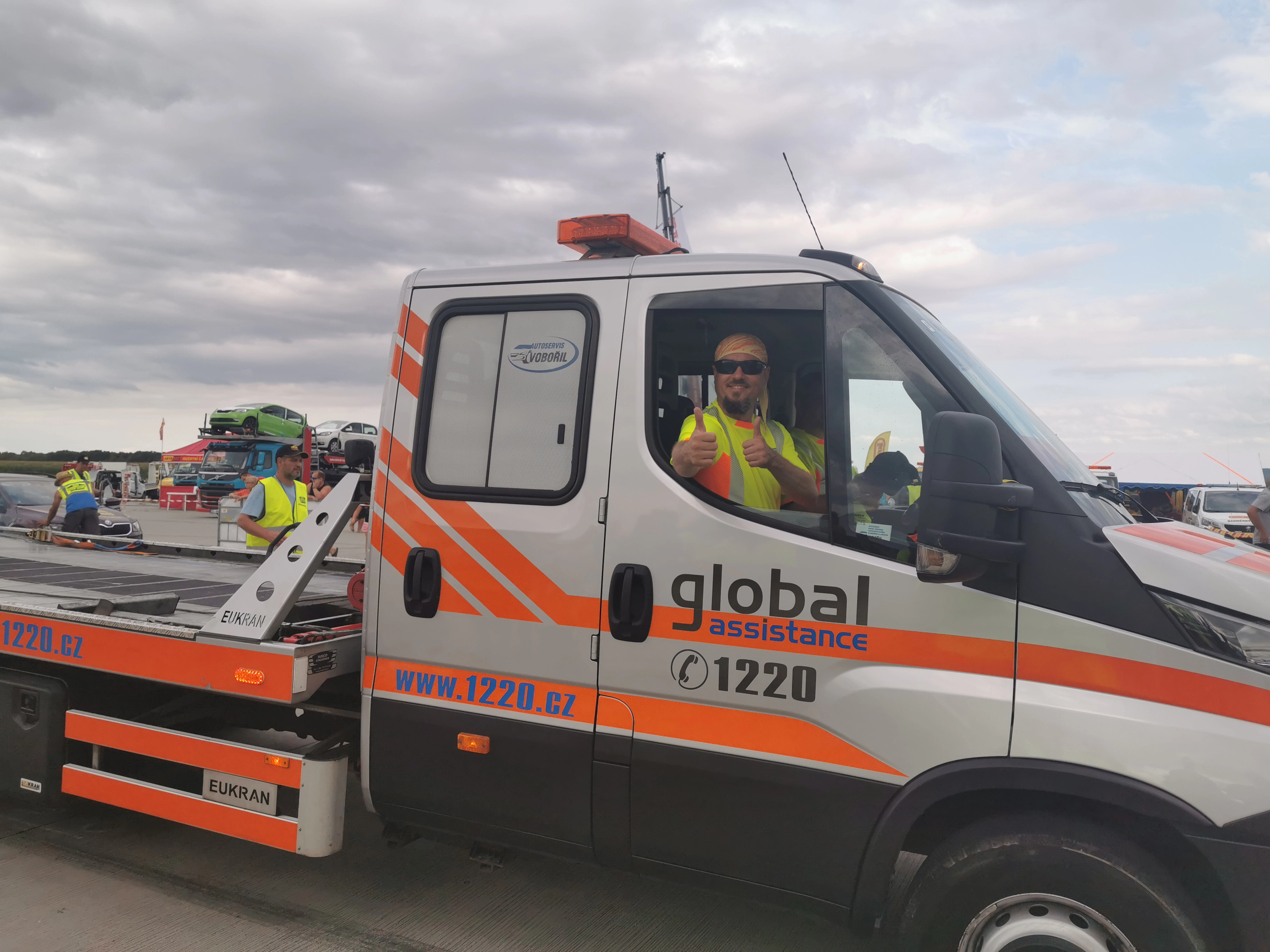 Man in a “Global Assistance” car with thumbs up