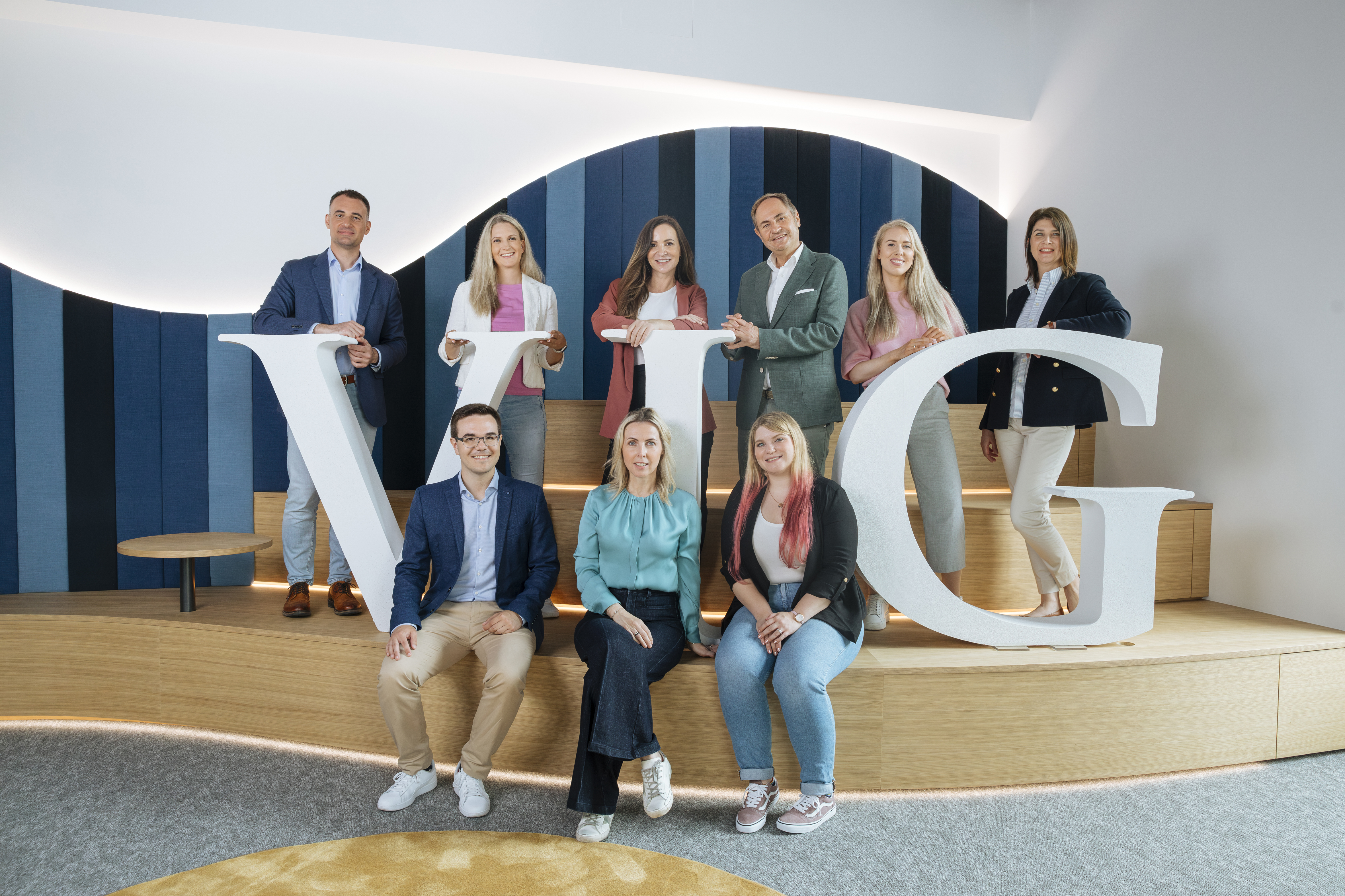 Team on wooden platform with large VIG letters