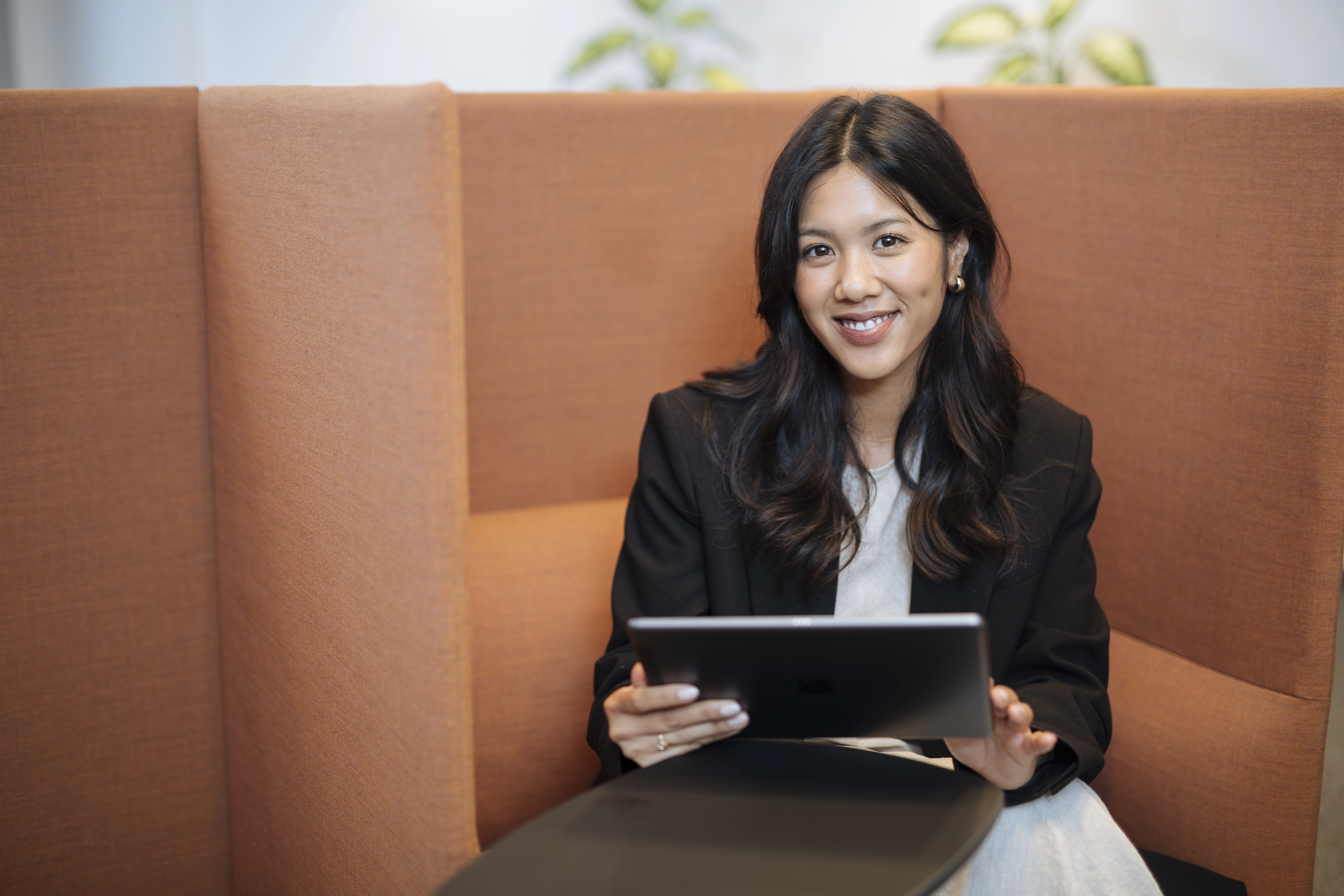 young employee is sitting on a sofa chair with a tablet in her hands