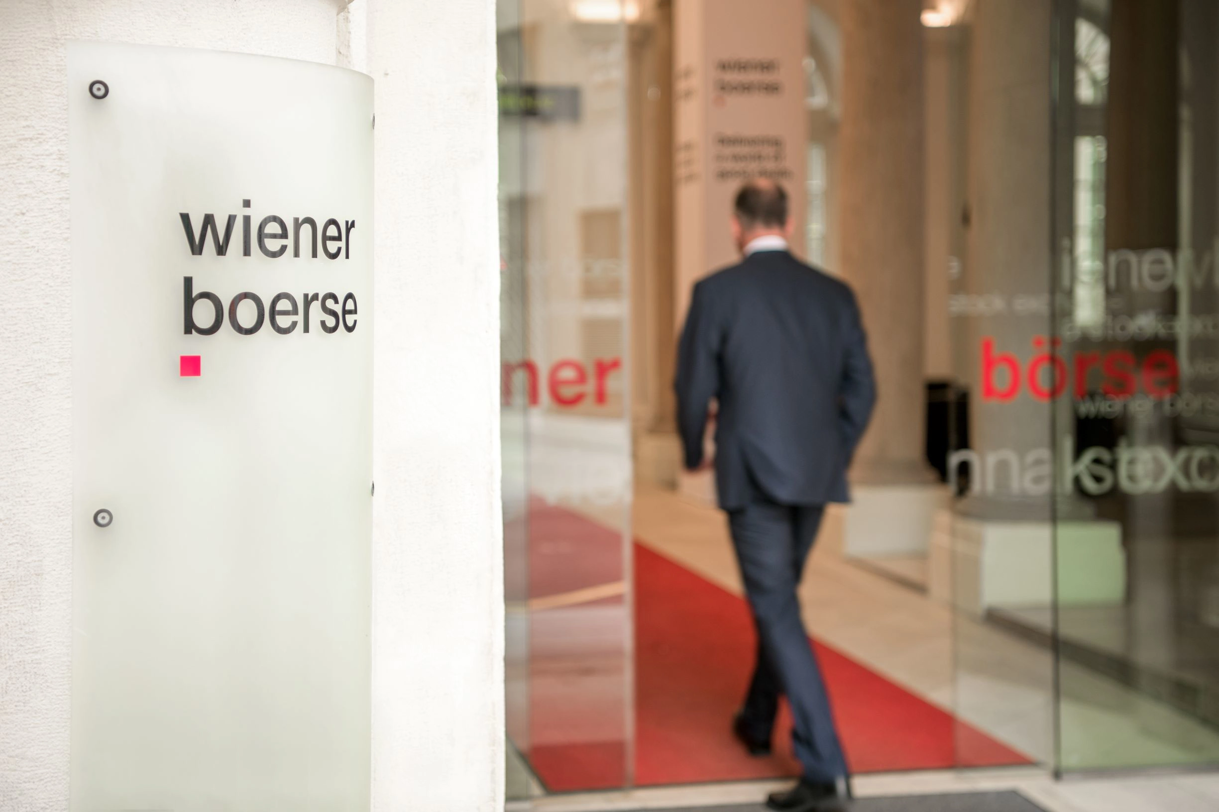 Man enters the building of the Vienna Stock Exchange through glass doors