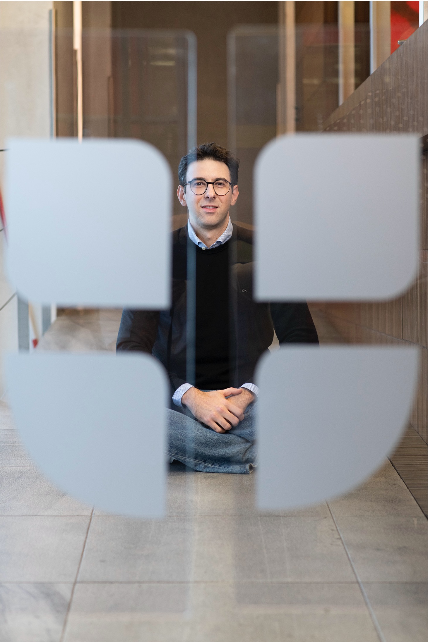 VIG Mitarbeiter im Eingangsbereich sitzend hinter gebrandeter Glastüre